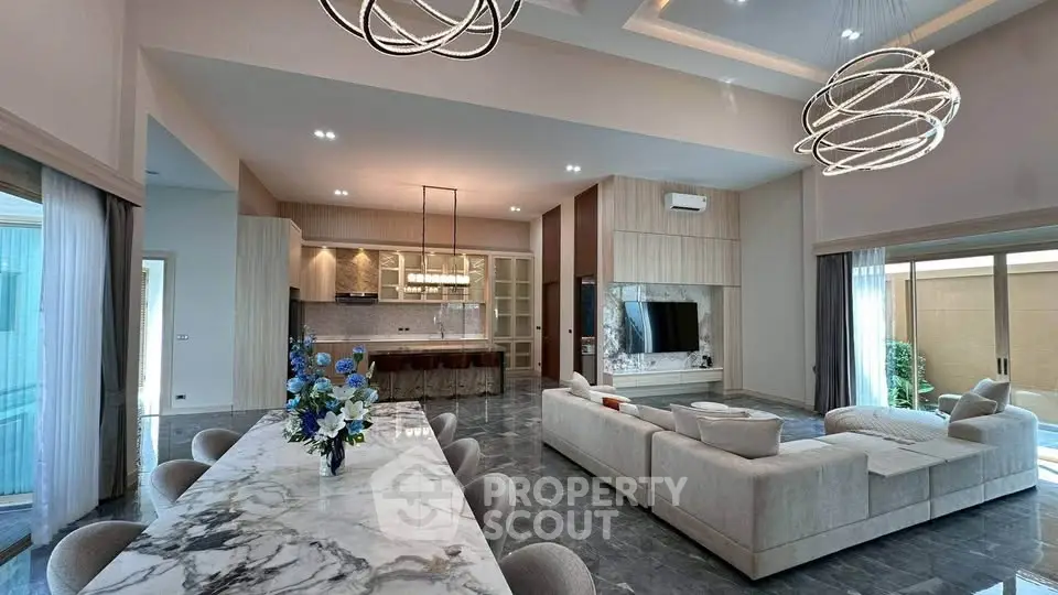 Luxurious open-plan living room with modern kitchen and elegant dining area, featuring stylish lighting and marble finishes.