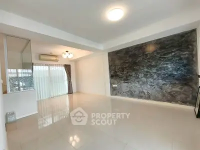 Spacious modern living room with unique textured wall and ample natural light.