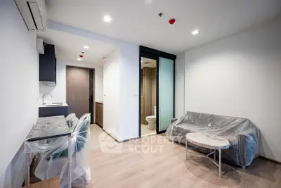 Modern apartment interior with compact kitchen and living area, featuring sleek design and natural lighting.