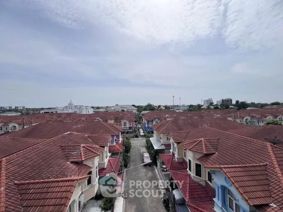 Aerial view of suburban neighborhood with red-tiled roofs and clear sky.