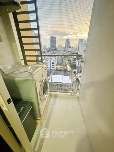Compact balcony with washing machine and stunning city view at sunset