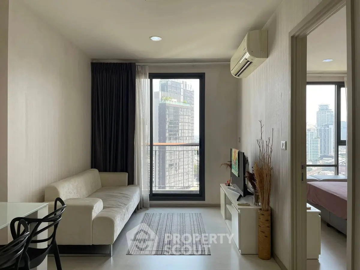 Modern living room with city view, featuring sleek furniture and large window for natural light.