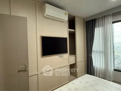 Modern bedroom with built-in wardrobe and wall-mounted TV, featuring large window with city view.