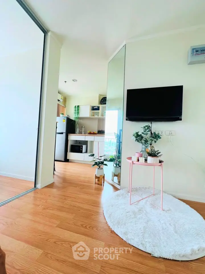 Modern living room with sleek TV, cozy rug, and stylish decor in a bright apartment.