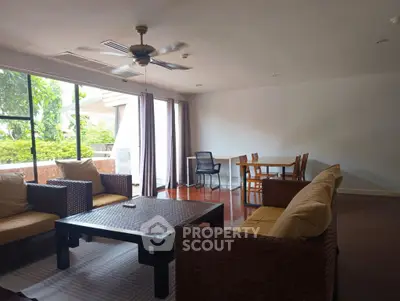 Spacious living room with modern furniture and large windows overlooking greenery.