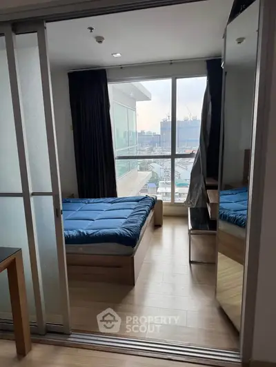 Modern bedroom with city view and sliding glass doors in high-rise apartment.