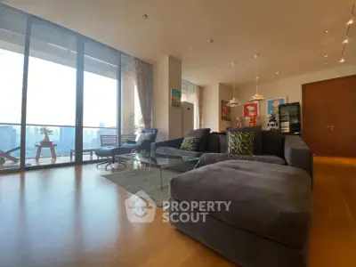 Spacious modern living room with large windows and city view balcony.