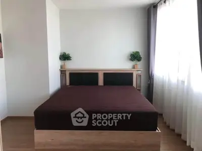 Spacious bedroom with modern decor and large window for natural light.