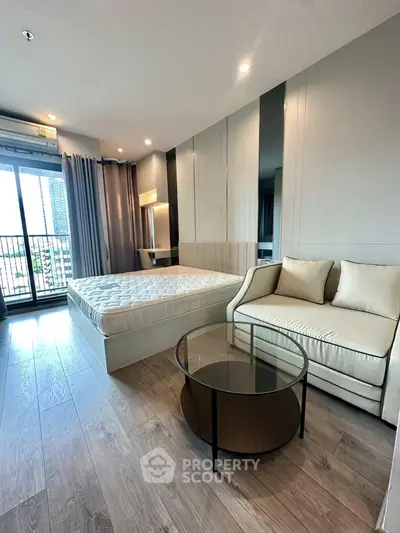Modern bedroom with stylish decor, featuring a cozy bed, elegant sofa, and a glass coffee table, offering city views.