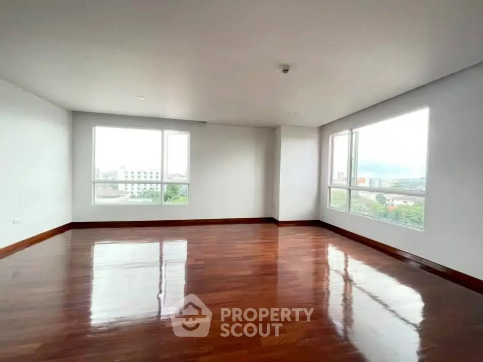 Spacious corner unit with polished hardwood floors and large windows offering city views.