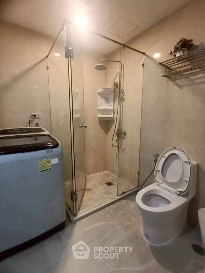 Modern bathroom with glass shower and washing machine in a sleek design.