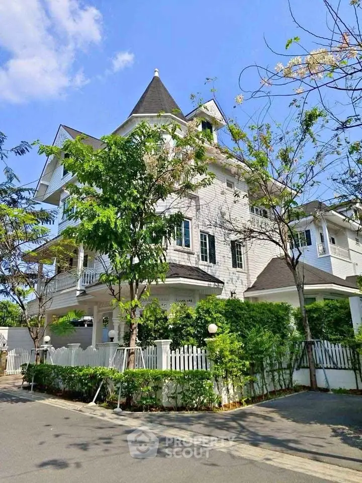 Charming Victorian-style house with lush greenery and elegant architecture in a serene neighborhood.
