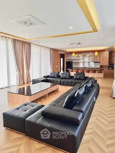 Luxurious modern living room with sleek black sofas and open kitchen layout