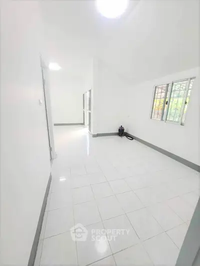 Spacious white-tiled room with large windows and ample natural light