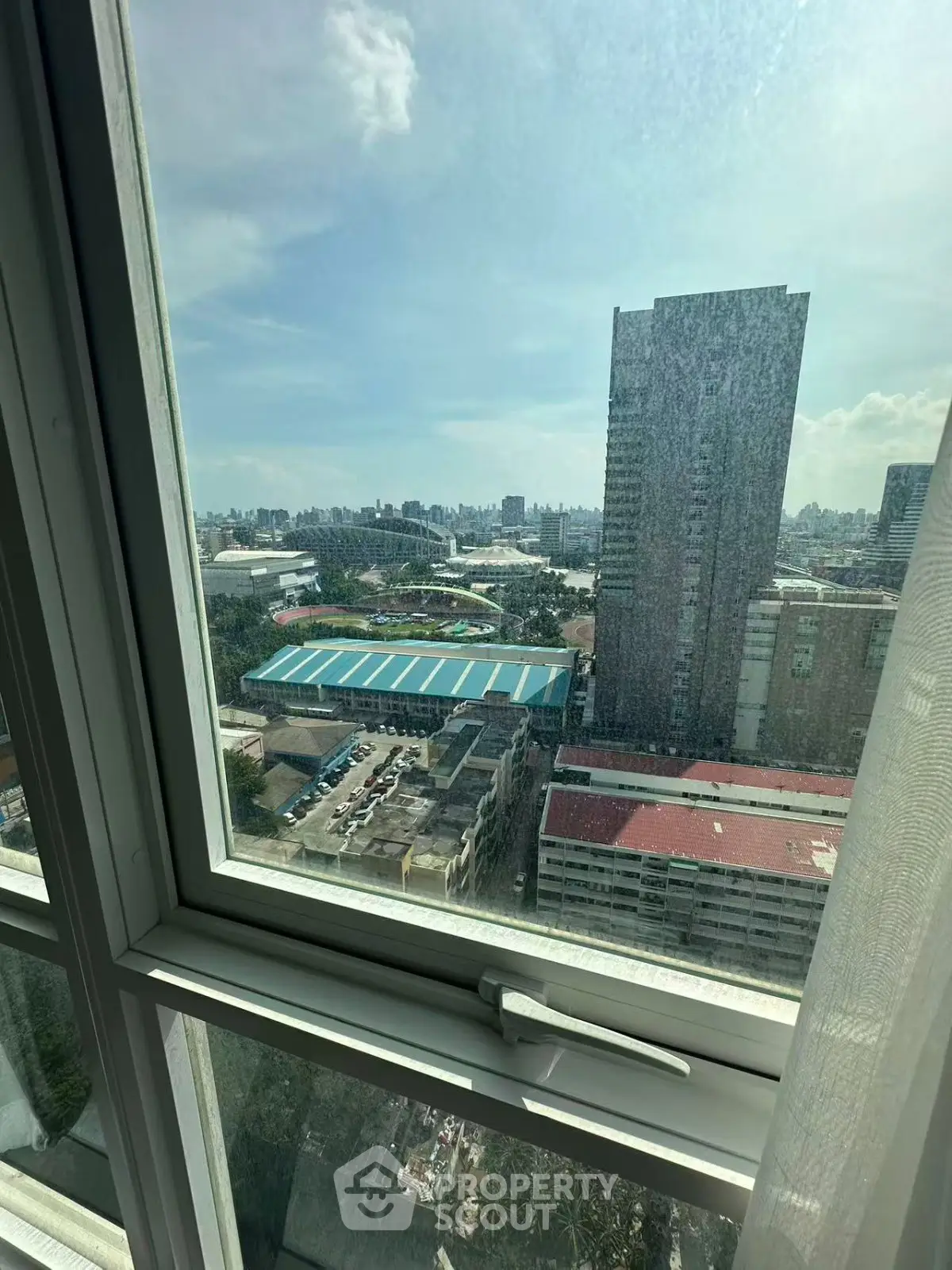 Stunning cityscape view from high-rise apartment window, showcasing urban skyline and clear blue sky.