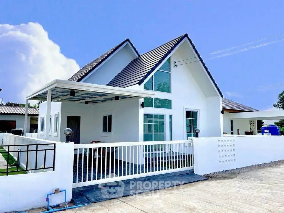 Charming modern white house with pitched roof and spacious front yard, perfect for family living.
