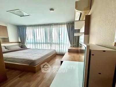 Cozy bedroom with large window and modern furnishings, perfect for relaxation.