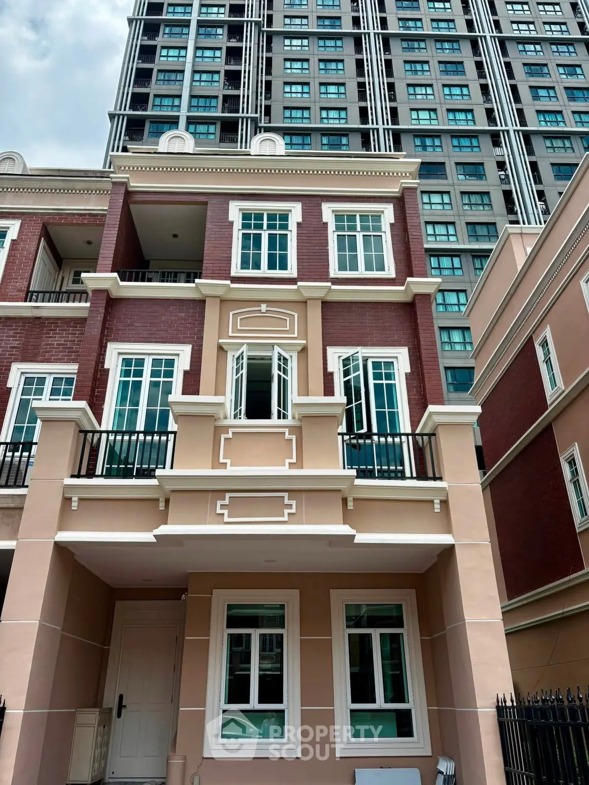 Stunning multi-story townhouse with elegant facade and modern windows, set against a backdrop of a high-rise building.