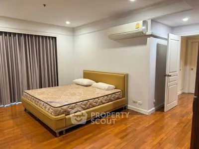Spacious bedroom with wooden flooring and modern air conditioning unit.