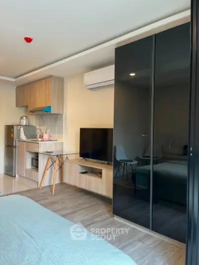 Modern studio apartment with sleek furniture and compact kitchen area.