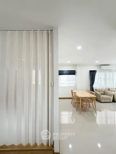 Spacious modern living room with dining area, featuring sleek flooring and ample natural light.