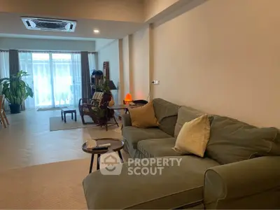 Spacious living room with cozy sofa and natural light, perfect for relaxation and entertaining.