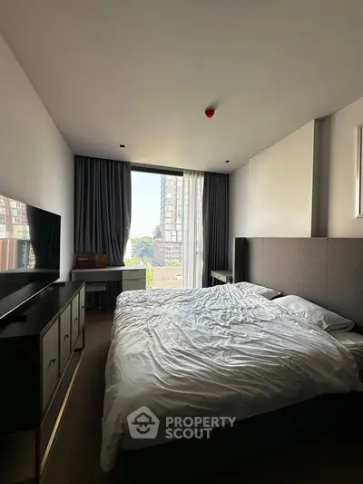 Modern bedroom with large window and stylish furnishings in urban apartment