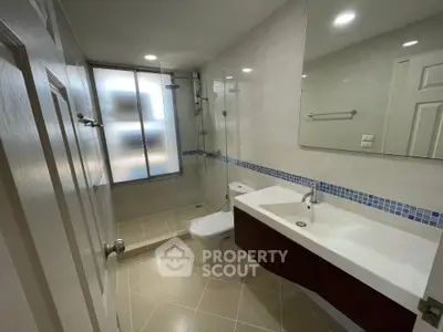 Modern bathroom with glass shower and sleek vanity in a bright setting.