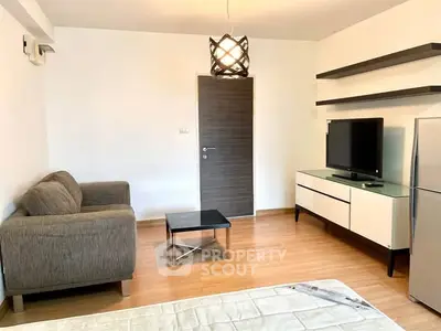 Modern living room with stylish furniture and TV, featuring wooden flooring and contemporary lighting.