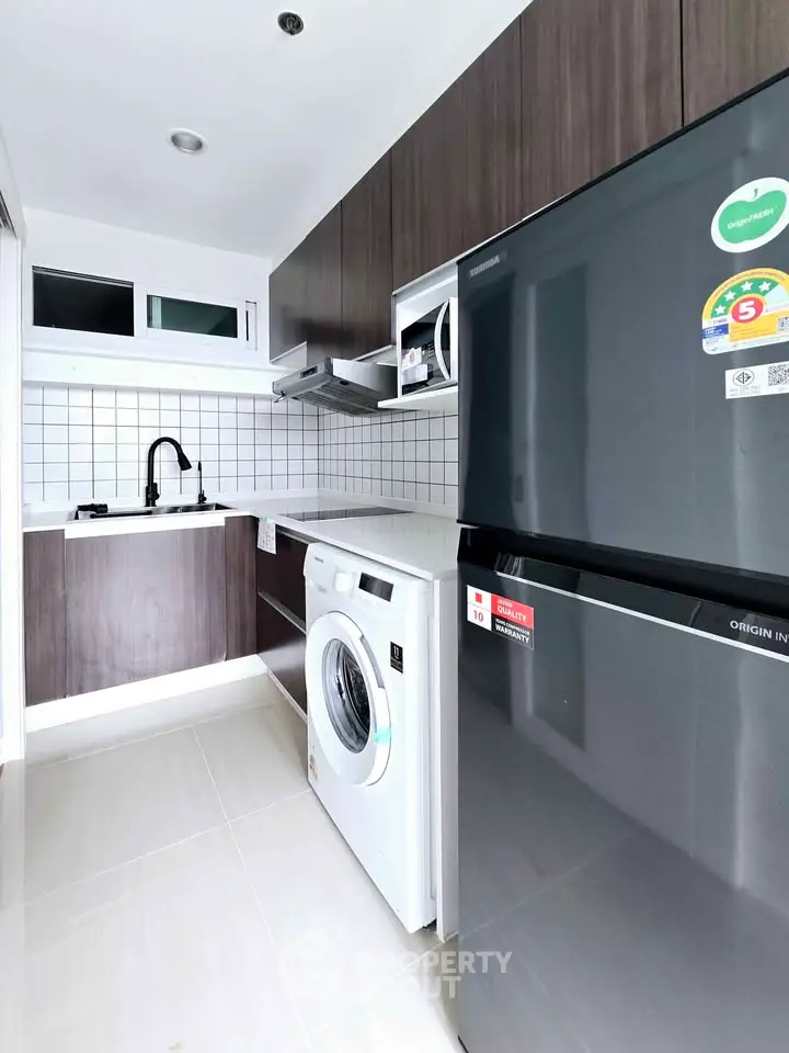 Modern kitchen with sleek appliances and stylish cabinetry in a compact layout.