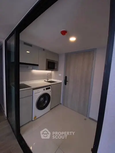 Modern compact kitchen with washing machine and microwave in sleek apartment