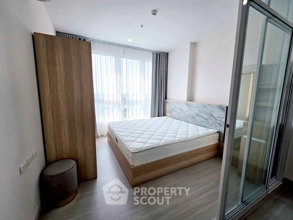 Modern bedroom with large window and minimalist design, featuring a comfortable bed and sleek wooden flooring.