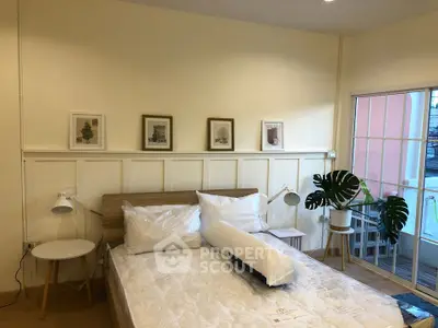 Cozy bedroom with modern decor and natural light from large window.