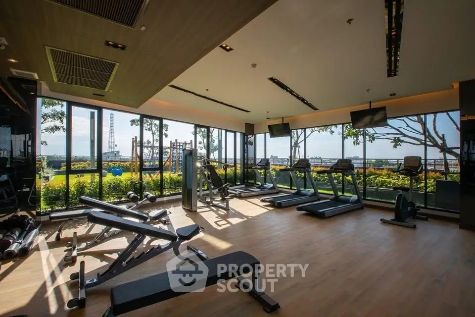 Spacious gym with modern equipment and panoramic city views, perfect for fitness enthusiasts.