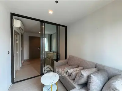 Modern living room with glass partition and cozy gray sofa in a stylish apartment.