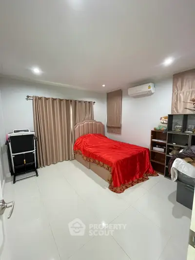 Cozy bedroom with red bedding, air conditioning, and ample storage space.