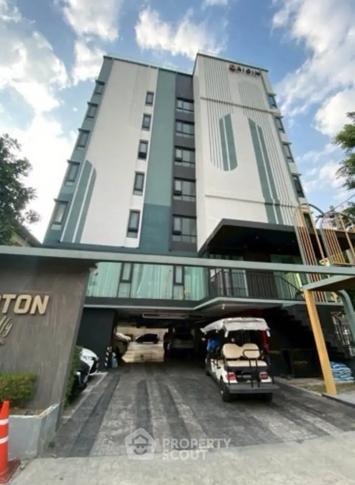 Modern multi-story building with parking area and clear blue sky, ideal for urban living.