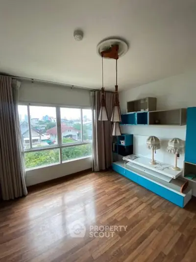 Spacious bedroom with large window and modern decor in a bright home.