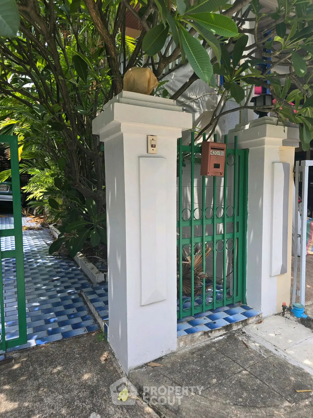 Charming garden entrance with green gate and lush foliage, perfect for a serene home setting.