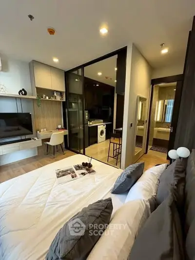 Modern bedroom with stylish decor and open layout featuring a cozy workspace and sleek bathroom view.