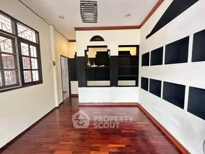 Spacious room with wooden flooring and built-in black shelves, ideal for a modern living space.