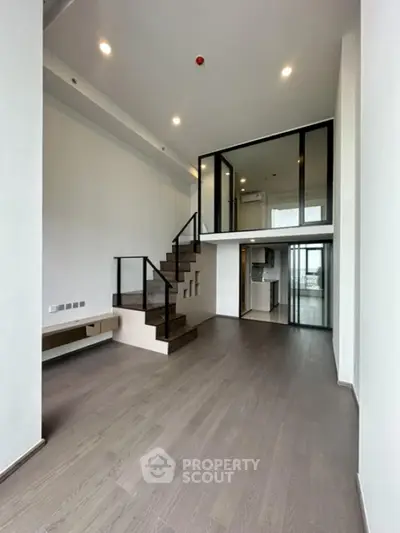 Modern duplex apartment with sleek staircase and open layout, featuring high ceilings and contemporary design.