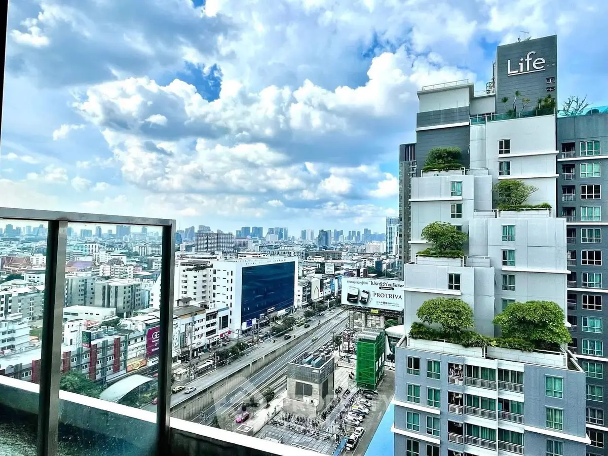 Stunning cityscape view from a modern high-rise balcony with lush greenery and clear skies.