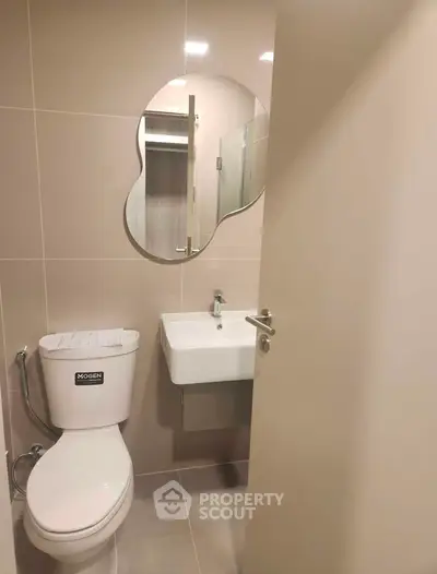 Modern bathroom with unique mirror and sleek fixtures in a contemporary apartment.