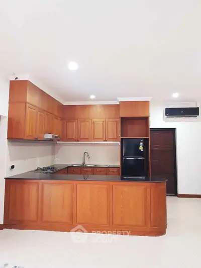 Spacious kitchen with wooden cabinetry and modern appliances in a stylish open layout.