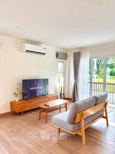 Bright and airy living room with modern wooden furniture and large windows overlooking greenery.