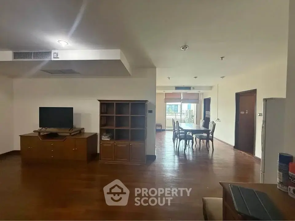 Spacious open-plan living and dining area with wooden flooring and modern furnishings.