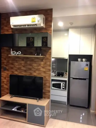 Modern living room with stylish decor and compact kitchen featuring microwave and fridge.
