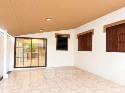 Spacious covered patio with elegant tile flooring and wooden accents, perfect for outdoor relaxation.