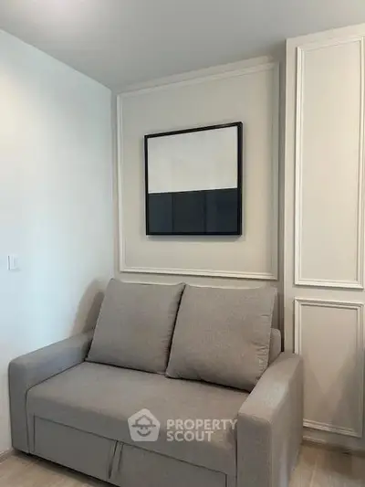 Modern living room with stylish gray sofa and minimalist wall art in a cozy apartment.